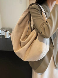 Person holding a beige handbag in an indoor setting