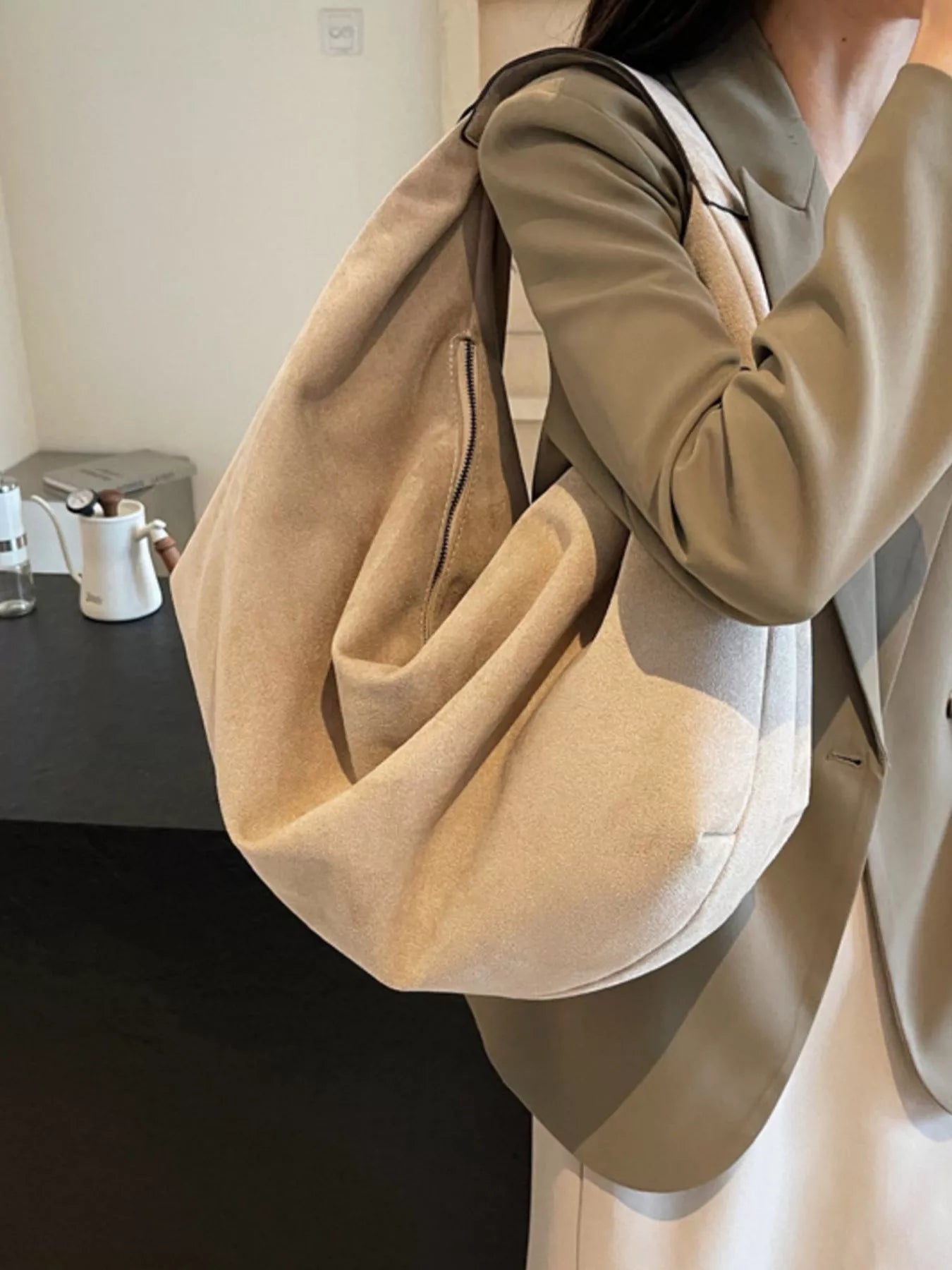 Person holding a beige handbag in an indoor setting