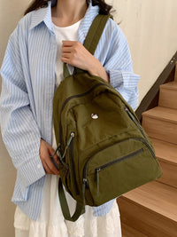 Person holding a green backpack in front of a wooden staircase