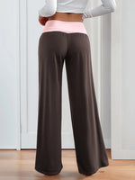 Person wearing brown wide-leg pants with a white top and pink waistband.
