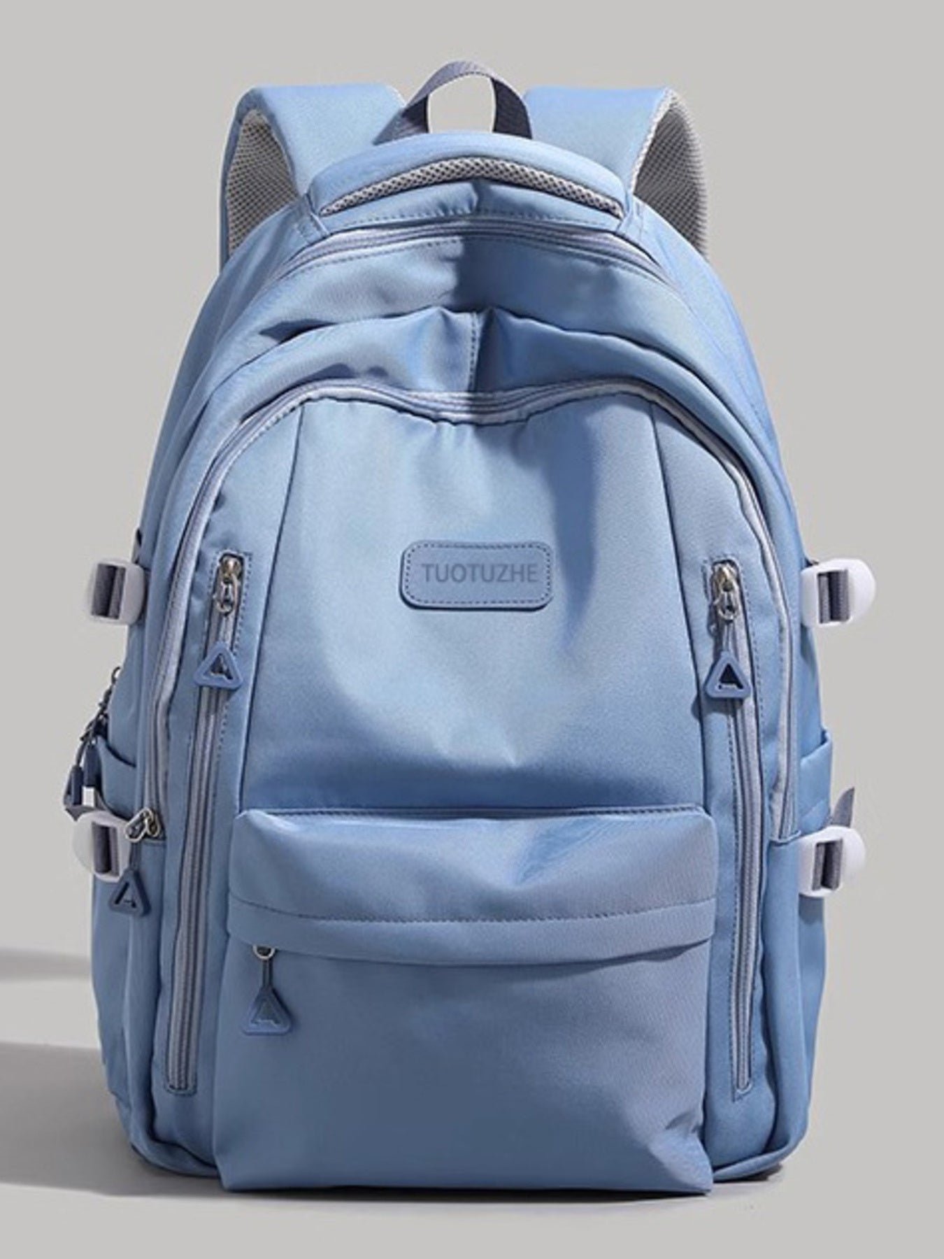Light blue backpack with multiple zippers on a gray background