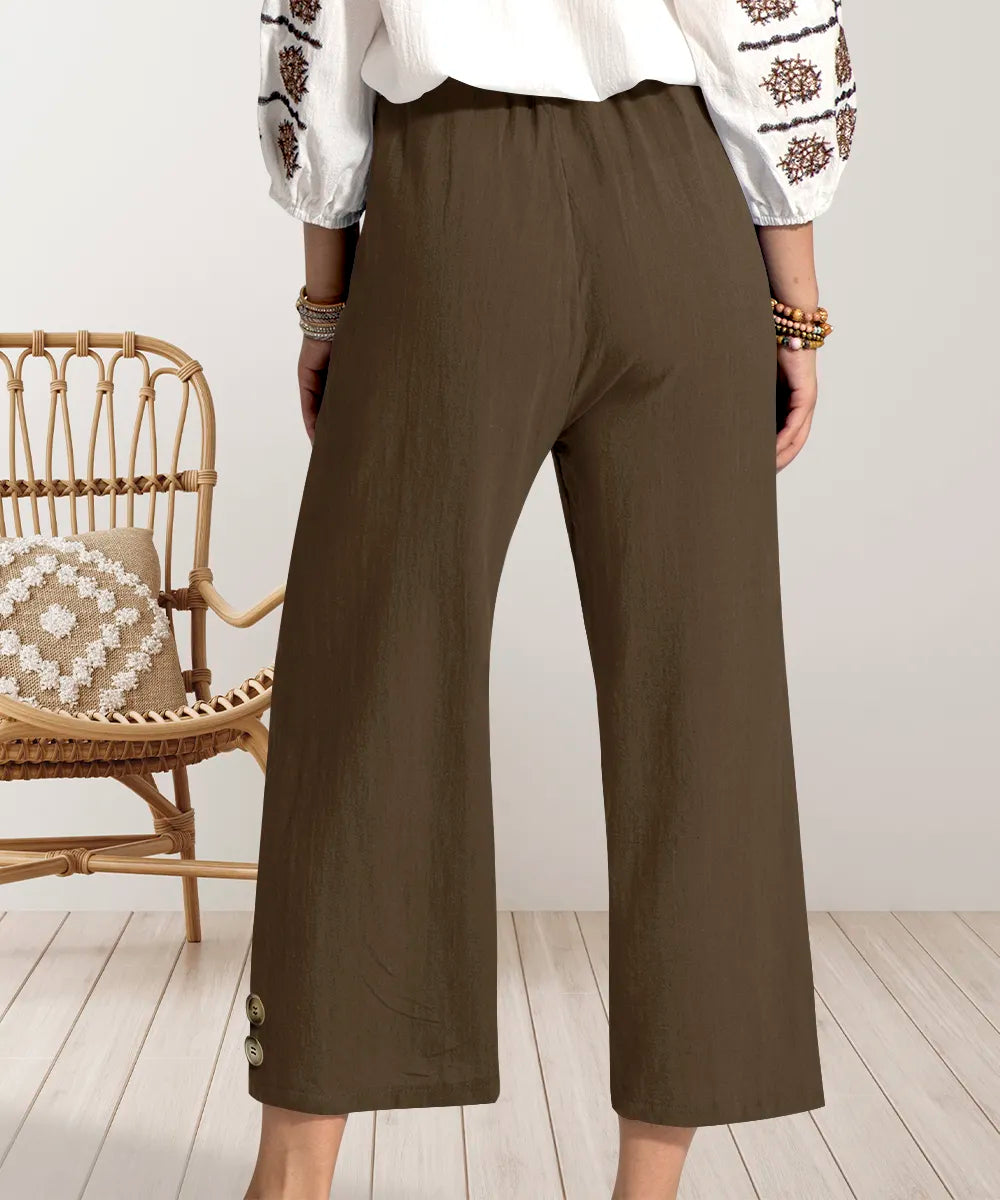 Person wearing brown wide-leg pants with a white top in a minimalistic room.