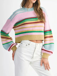 Person wearing a colorful striped sweater and white pants on a white background