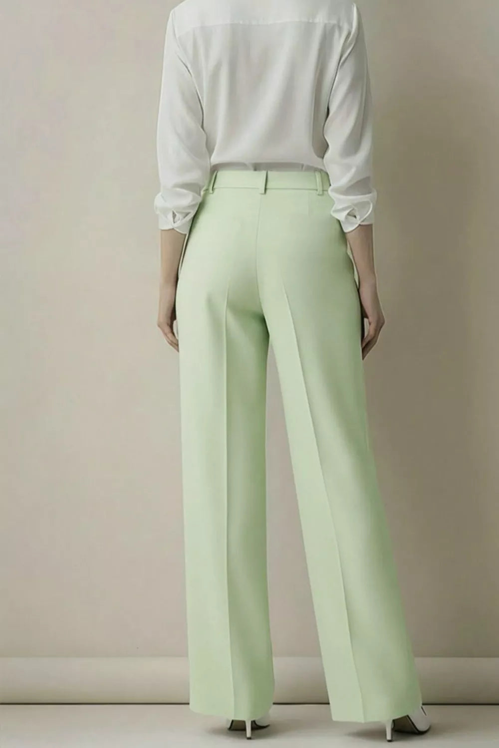 Person wearing a white shirt and light green pants against a plain background