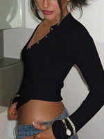 Person wearing a black long-sleeve top and denim shorts indoors.