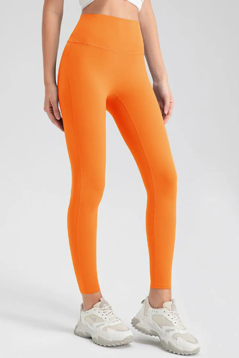 Person wearing bright orange leggings and white sneakers on a light gray background