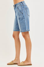 Denim shorts worn by a person on a plain background