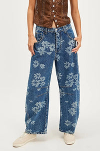 Person wearing blue jeans with floral patterns on a white background