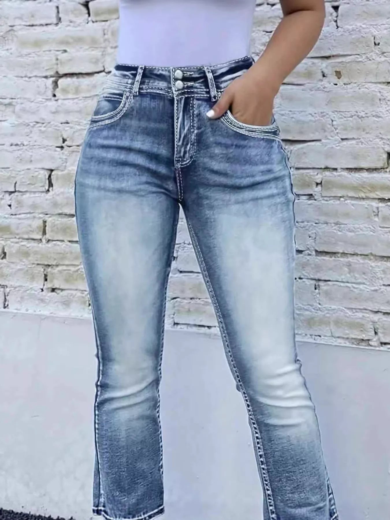 Person wearing light blue jeans against a stone wall background