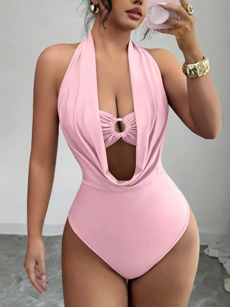 Woman wearing a pink halter neck swimsuit against a neutral background
