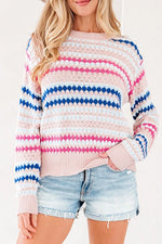 A woman wearing a pink knit sweater with horizontal stripes of blue, pink, and white, paired with light-wash denim shorts.