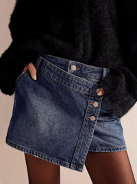 Person wearing a black fur coat and denim skirt on a beige background