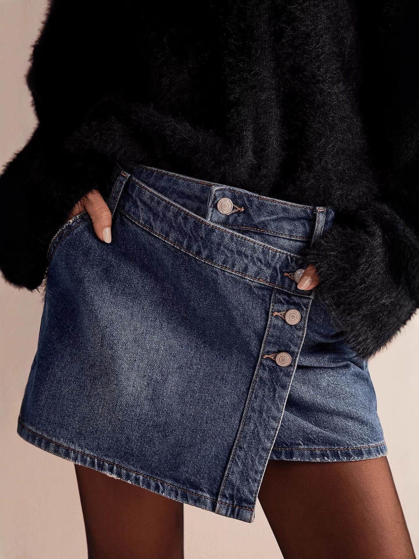 Person wearing a black fur coat and denim skirt on a beige background