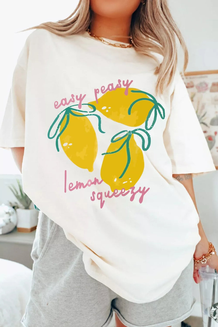 Person wearing a white t-shirt with lemon graphic and text in a casual setting