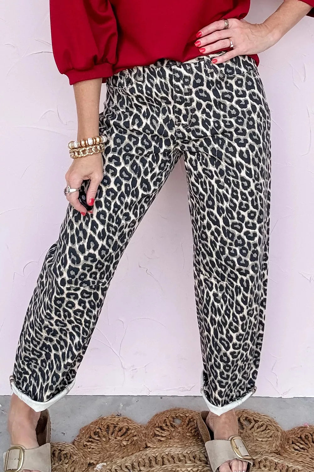 Person wearing leopard print pants and a red top against a white background