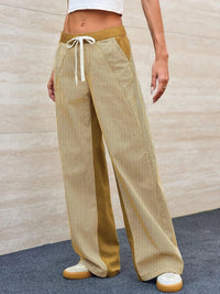 Person wearing mustard yellow wide-leg pants with a white background