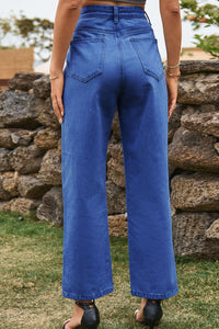 Person wearing blue jeans standing in front of a stone wall.