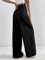 Person wearing black wide-leg pants against a white background