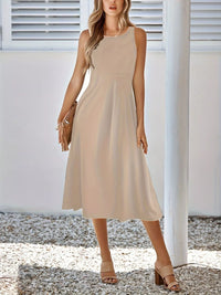 Woman wearing a beige dress standing outdoors with a neutral background