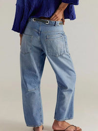 Person wearing blue jeans and a purple shirt on a plain background