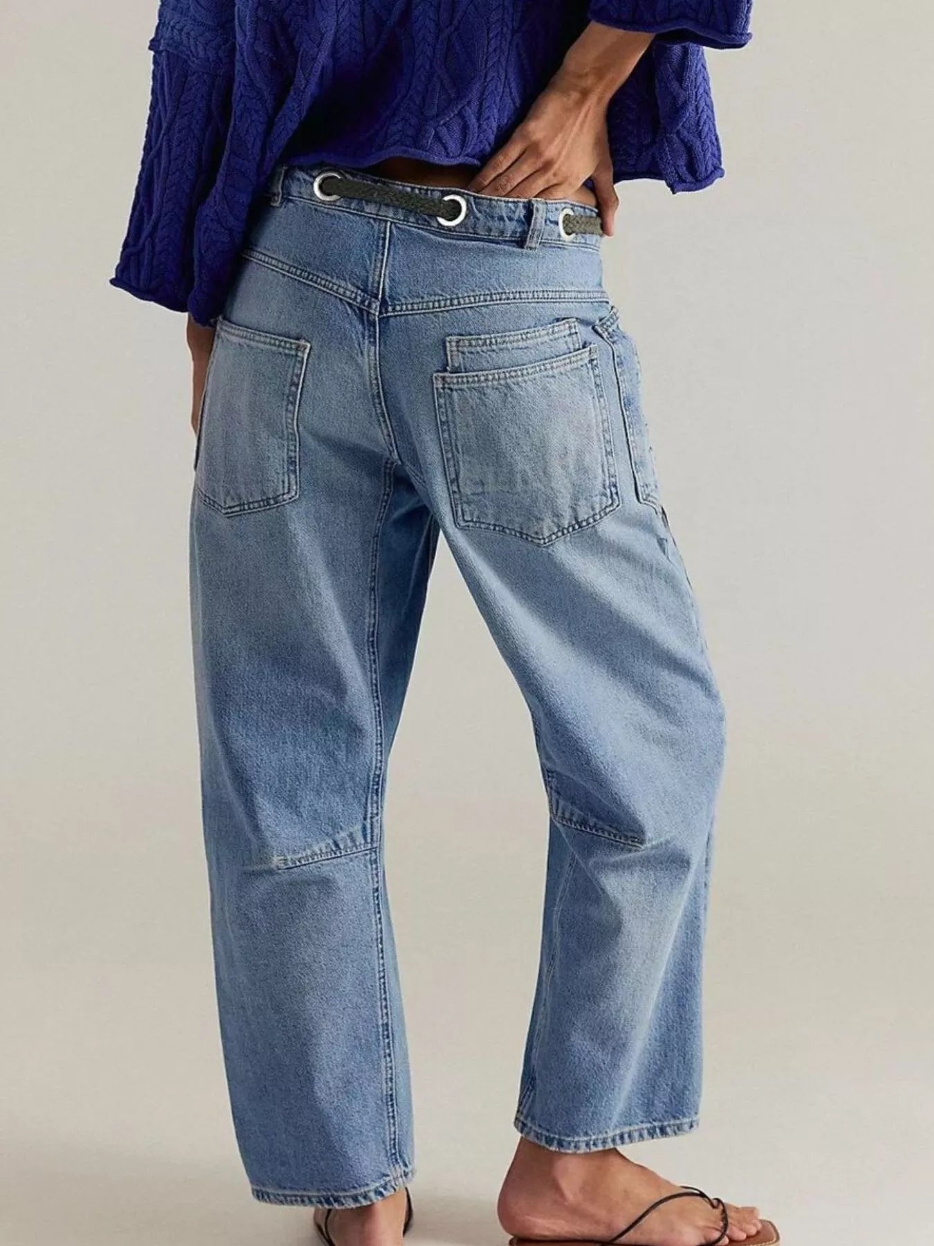 Person wearing blue jeans and a purple shirt on a plain background