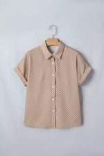 Beige short-sleeve shirt with a subtle pattern on a hanger against a light gray background