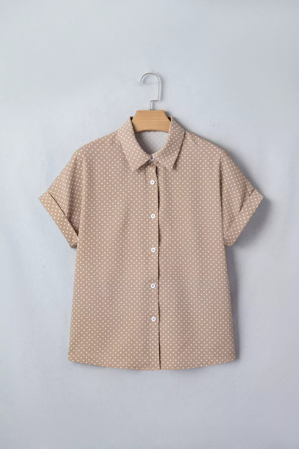 Beige short-sleeve shirt with a subtle pattern on a hanger against a light gray background