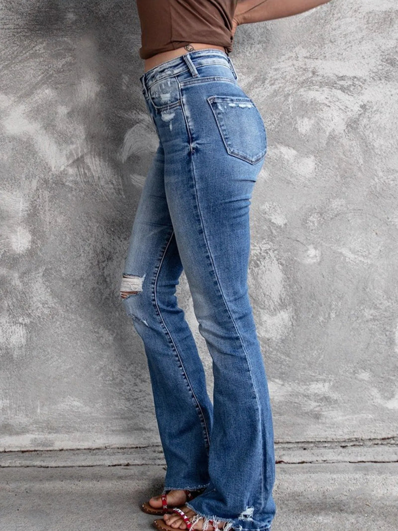 Person wearing blue jeans against a gray concrete wall