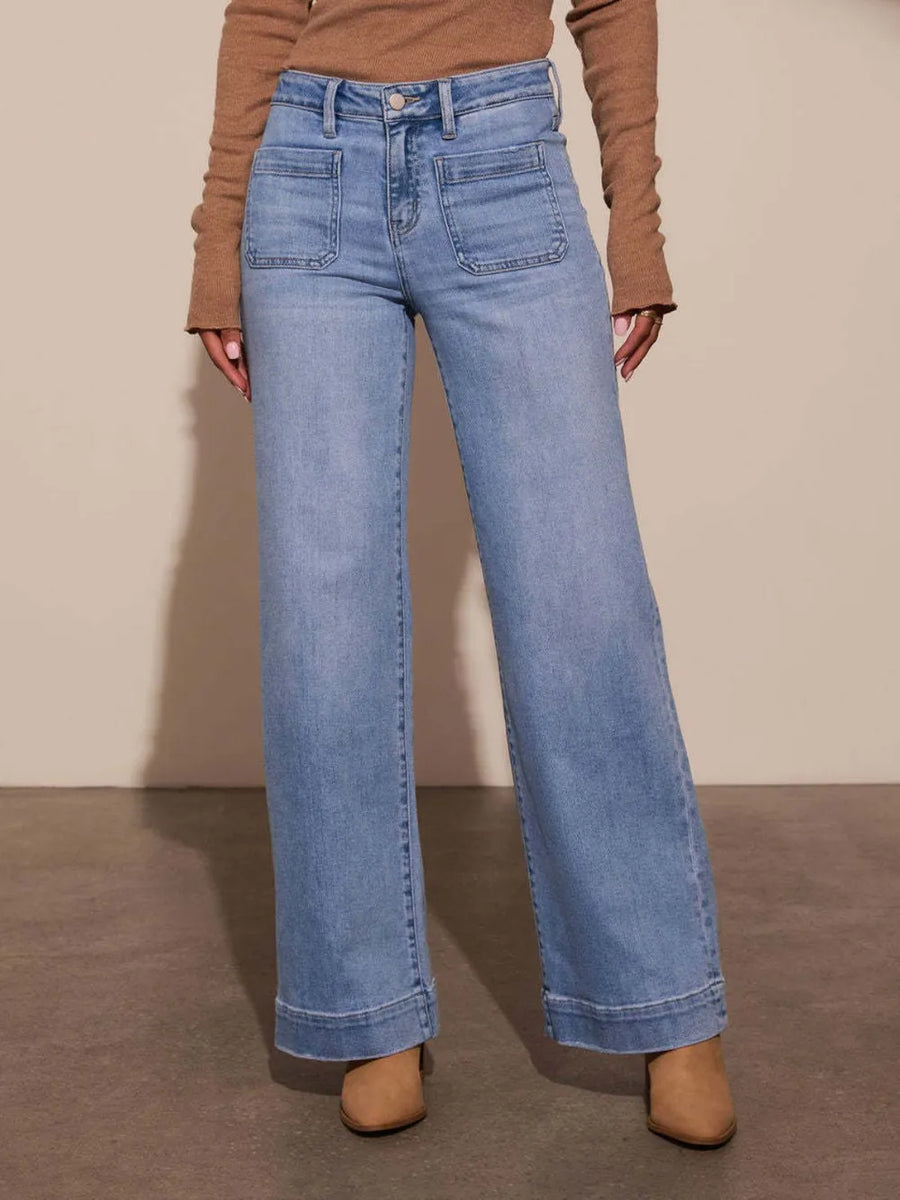 Person wearing blue jeans and a brown top on a neutral background