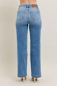 Blue jeans worn by a person on a beige background