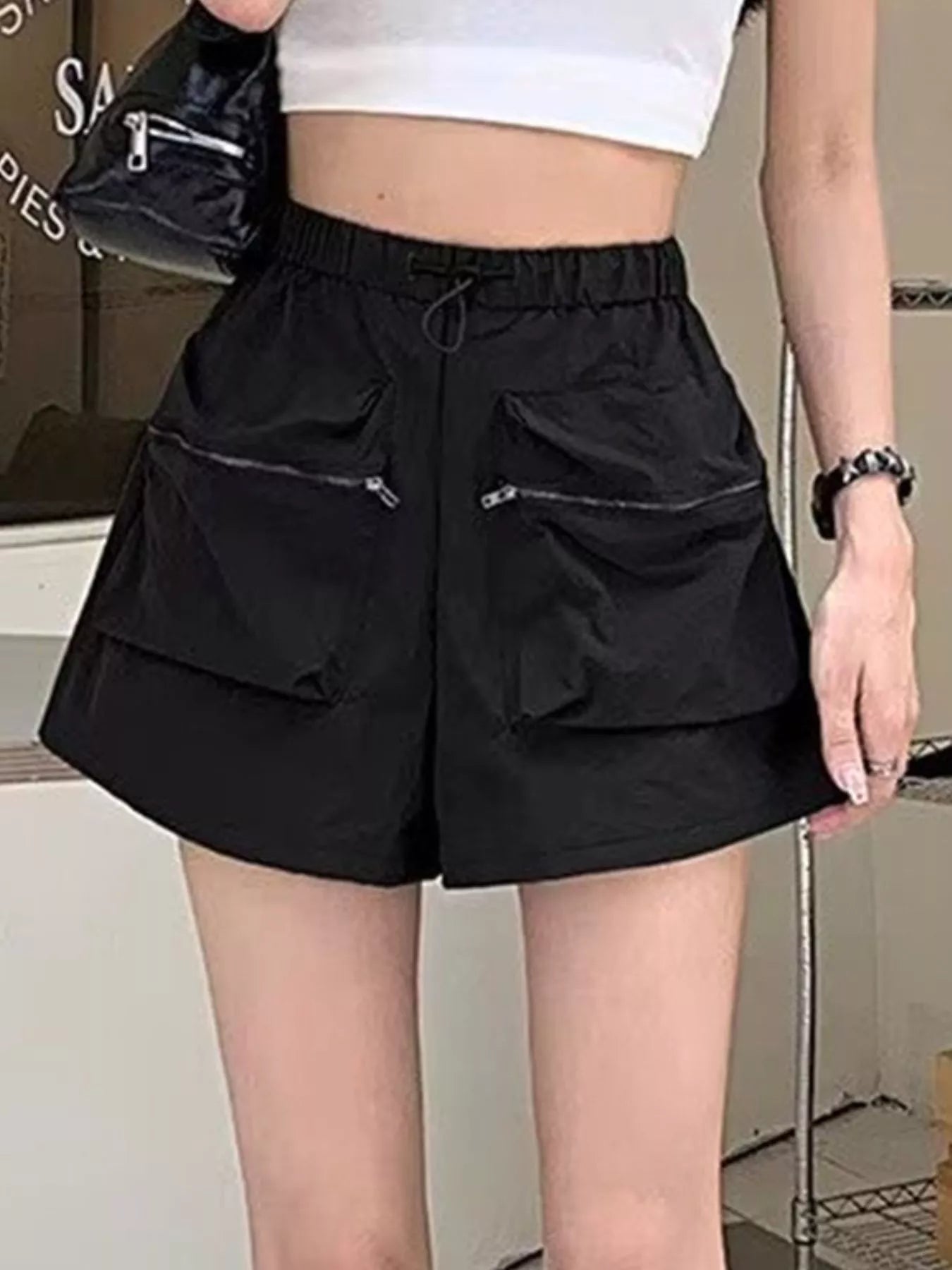 Person wearing black cargo shorts with multiple pockets indoors.