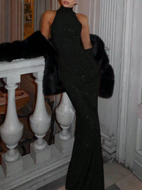 Woman wearing a black evening gown with fur trim indoors.