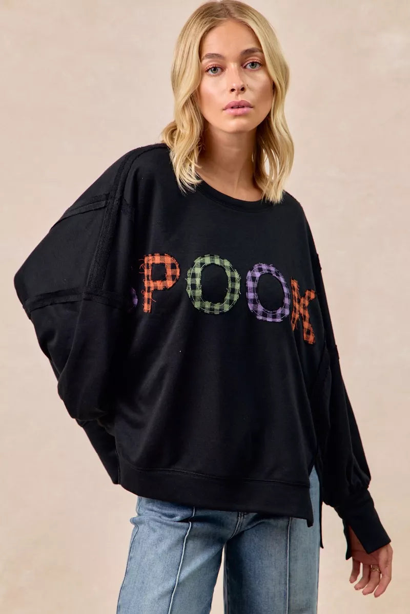 Person wearing a black sweatshirt with colorful 'POOH' text on a beige background