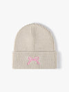 Beige knit beanie with a pink bow on a white background