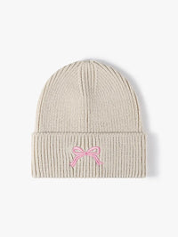 Beige knit beanie with a pink bow on a white background