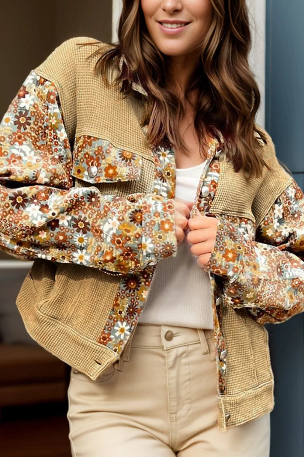 Woman wearing a floral embroidered jacket with a neutral background