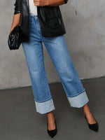 Person wearing blue jeans and black shoes on a gray background