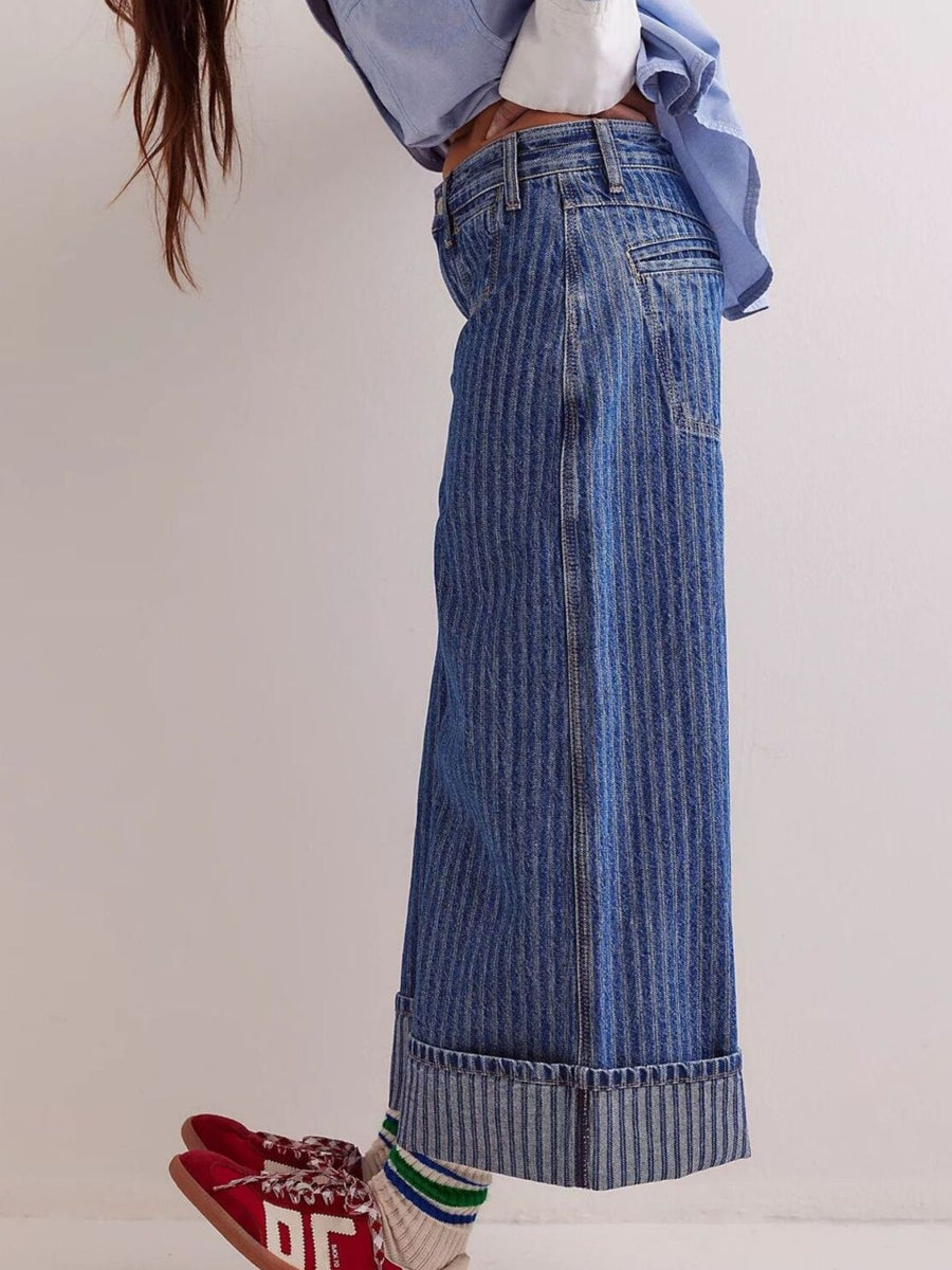 Person wearing blue wide-leg jeans with a plain background