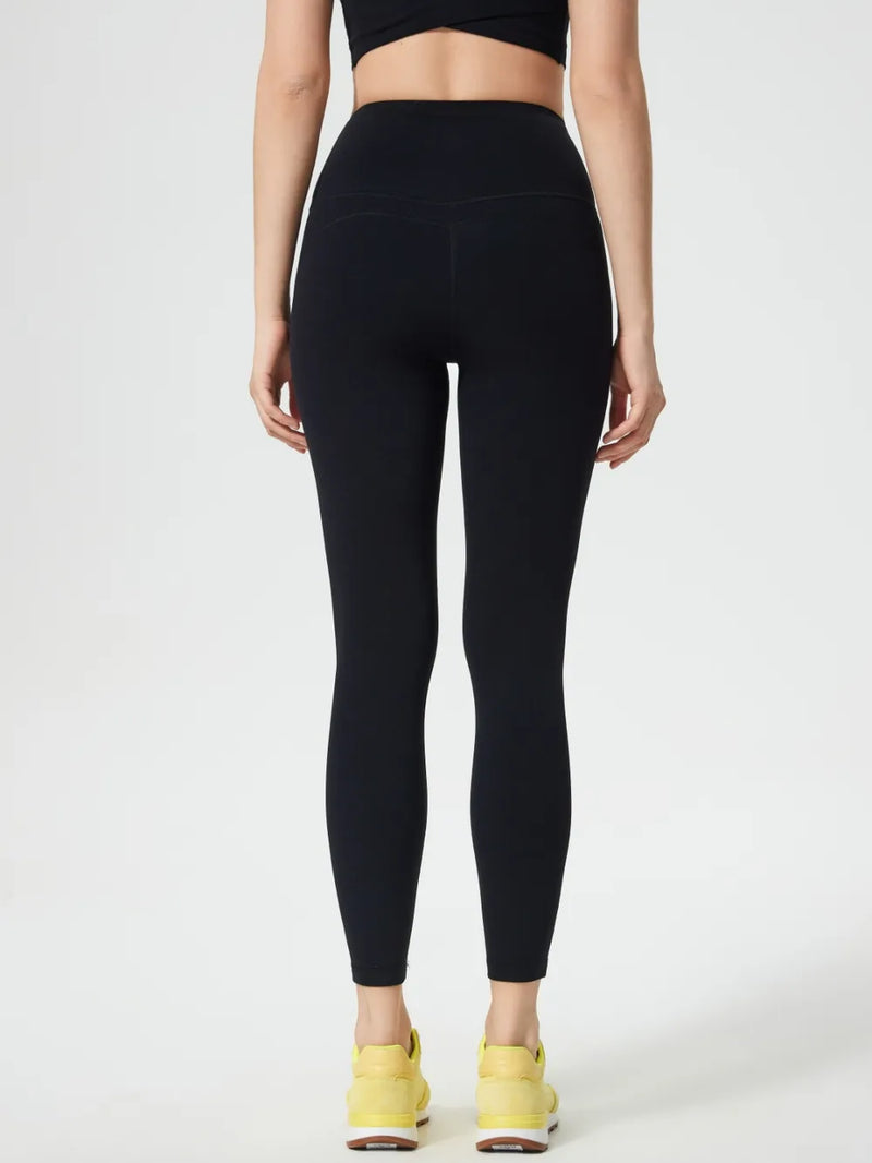 Person wearing black leggings and yellow sneakers on a white background