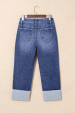 Blue jeans with cuffed hems on a beige background