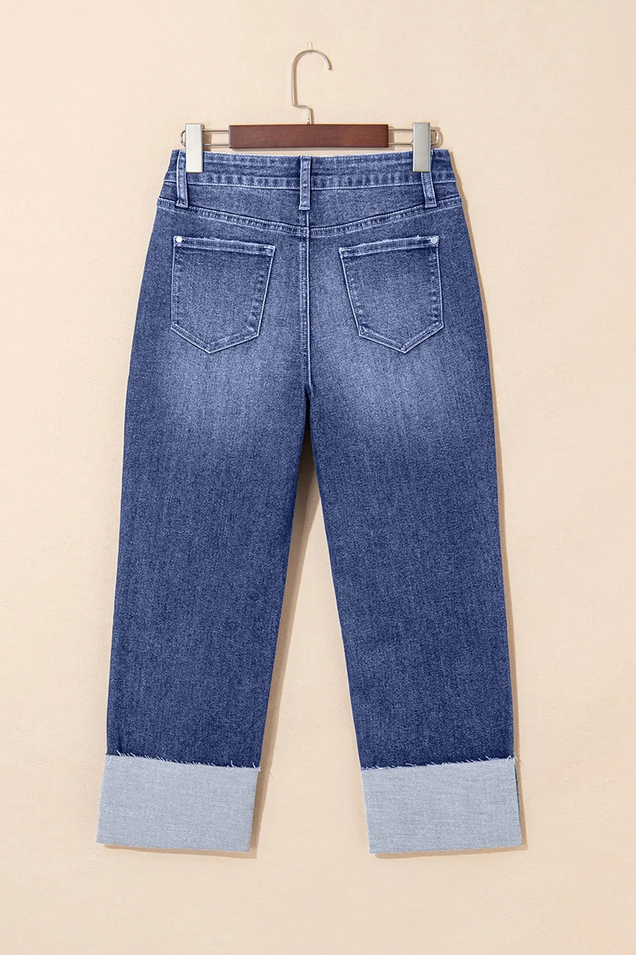 Blue jeans with cuffed hems on a beige background