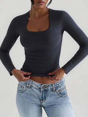 Person wearing a black long-sleeve top and blue jeans against a plain background