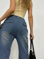 Person wearing blue jeans and a beige top against a plain background