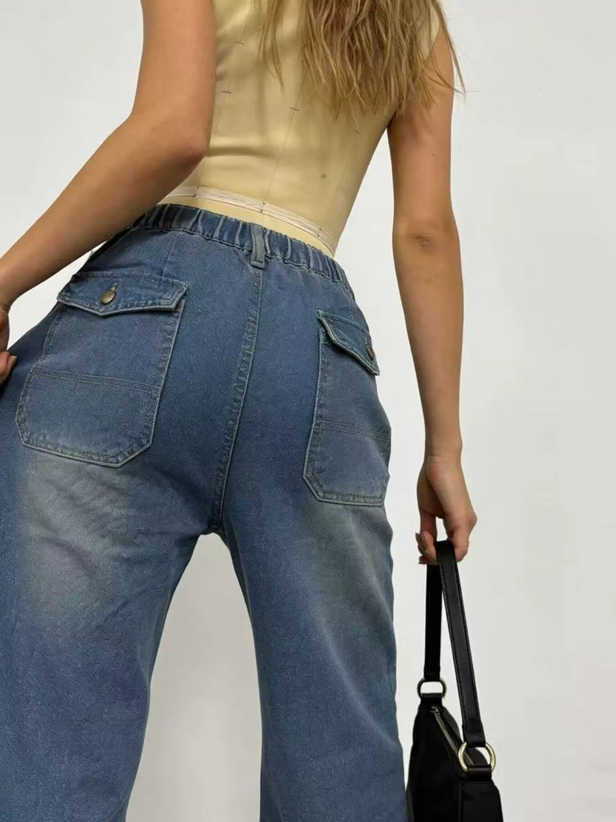 Person wearing blue jeans and a beige top against a plain background