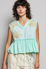 Woman wearing a light blue floral top against a plain background