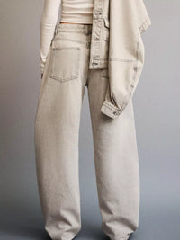 Light-colored jeans worn by a person on a gray background