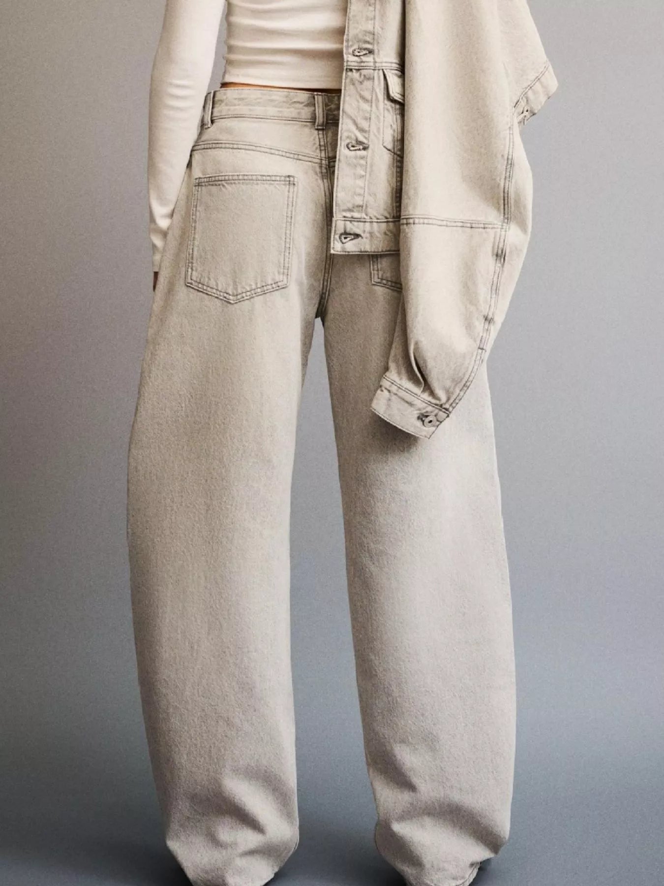 Light-colored jeans worn by a person on a gray background
