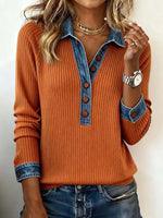 Person wearing an orange ribbed sweater with denim collar and cuffs on a plain background
