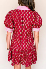 Red floral dress with pink trim worn by a person on a white background