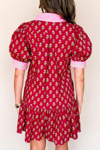Red floral dress with pink trim worn by a person on a white background
